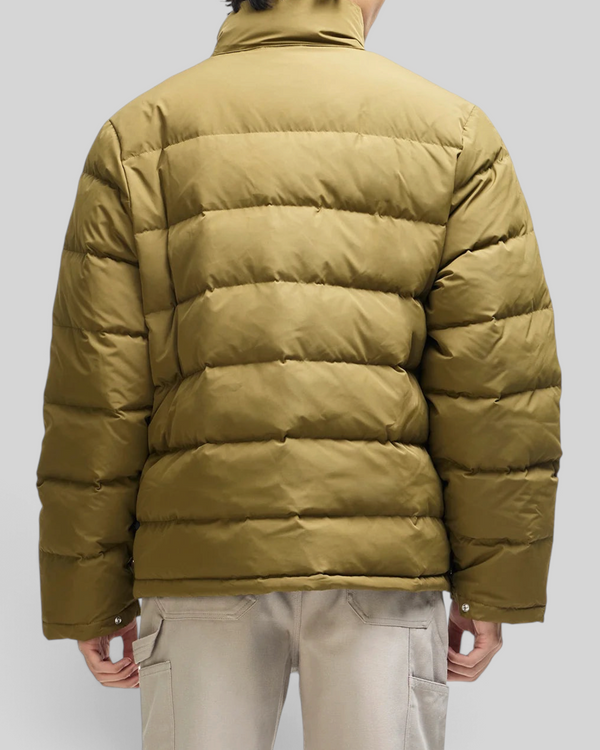 Back view of a person wearing a Baffle Haus olive green down jacket with a quilted design and high collar.