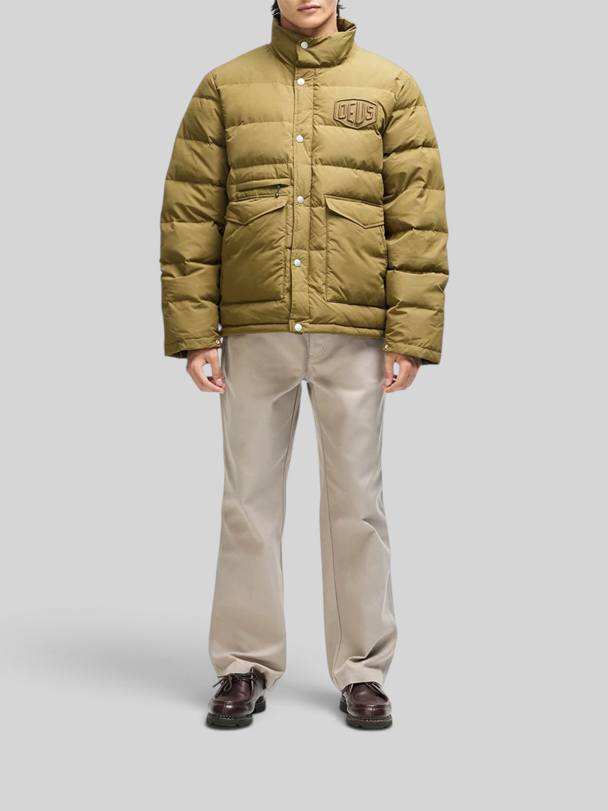 Baffle Haus Carson olive down jacket with chest branding, flap pockets, and zip front closure on a male model