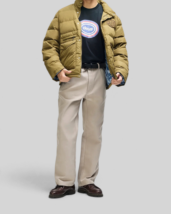 Baffle Haus Carson olive down jacket with patch pockets, worn by a model with a black graphic tee and beige trousers.
