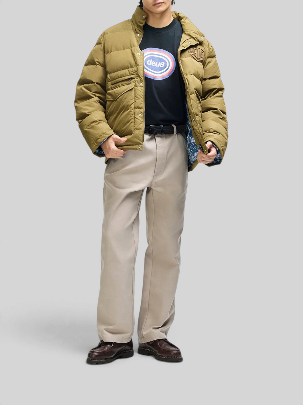 Baffle Haus Carson olive down jacket with patch pockets, worn by a model with a black graphic tee and beige trousers.