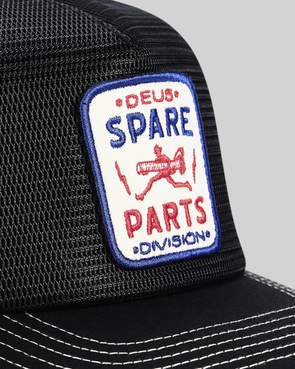 Baffle Haus Mudflap Trucker cap in black featuring a detailed embroidered Deus Spare Parts badge on polyester mesh