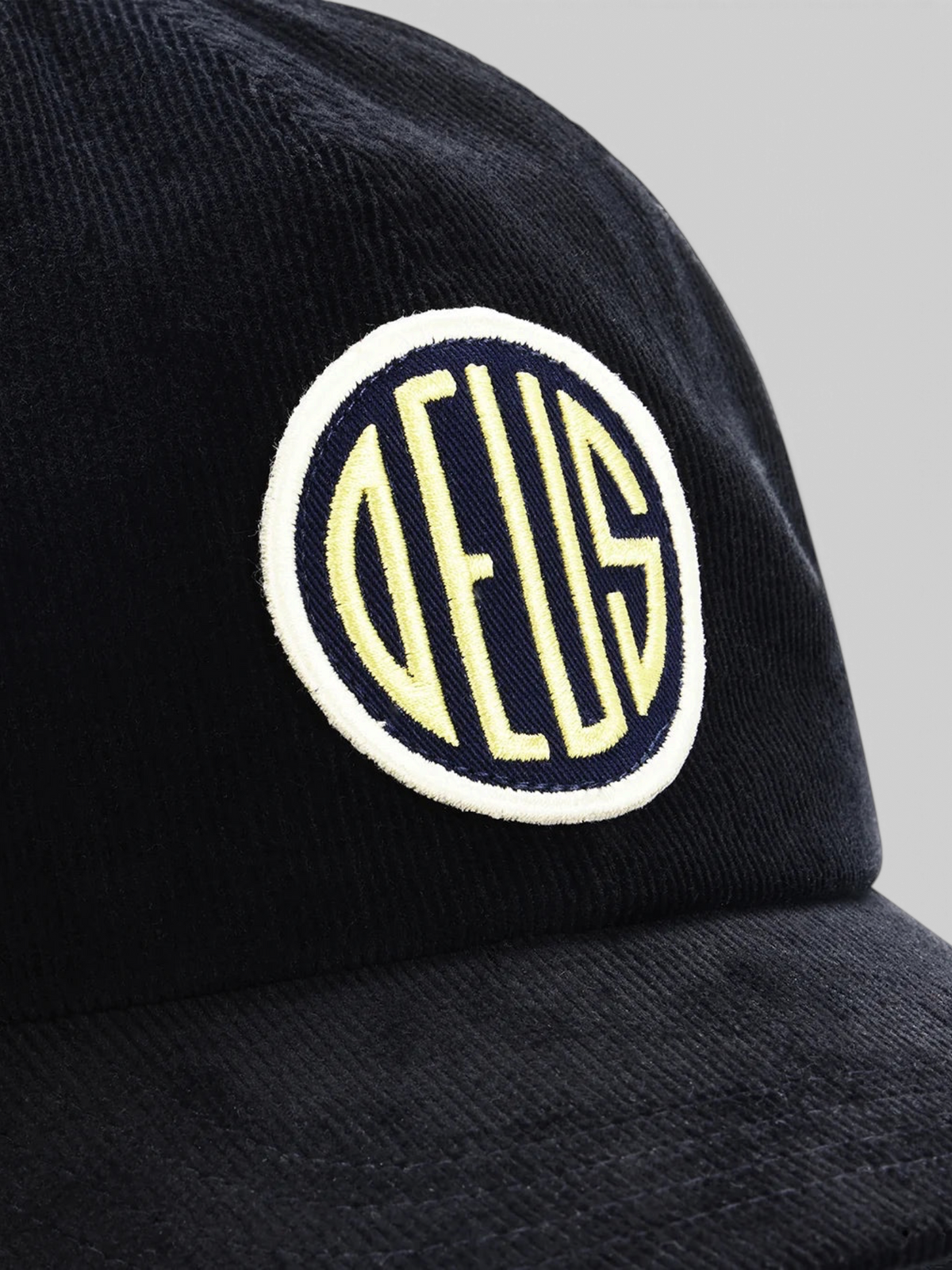 Baffle Haus black cotton corduroy trucker hat featuring a circular embroidered logo patch on the front
