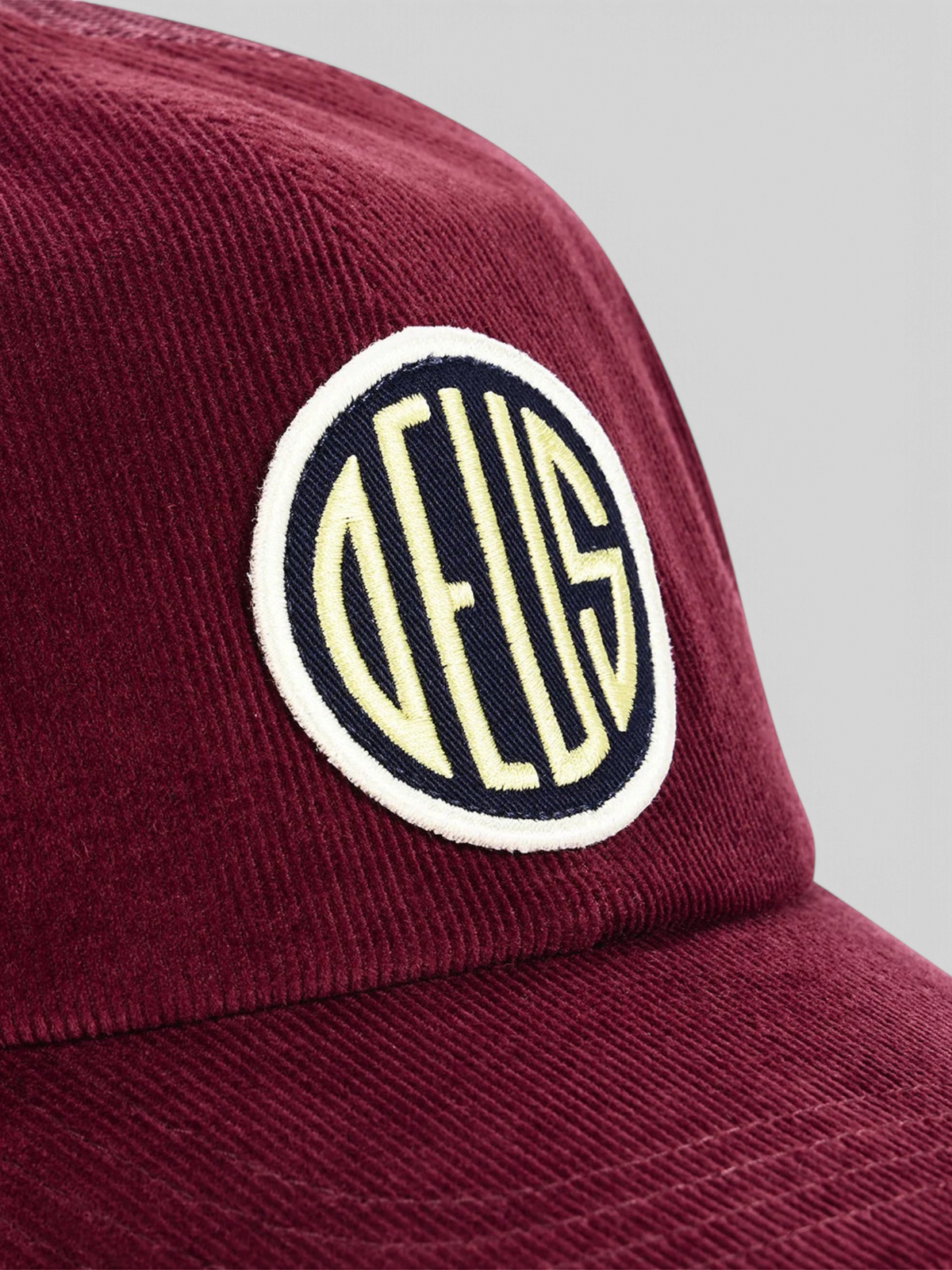 Baffle Haus burgundy cotton corduroy trucker hat featuring a circular embroidered logo patch on the front