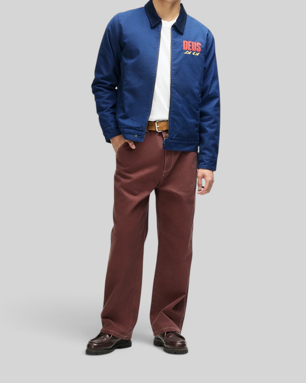 A model wearing a Baffle Haus navy cotton whipcord cutaway jacket with red chest embroidery and a corduroy collar.