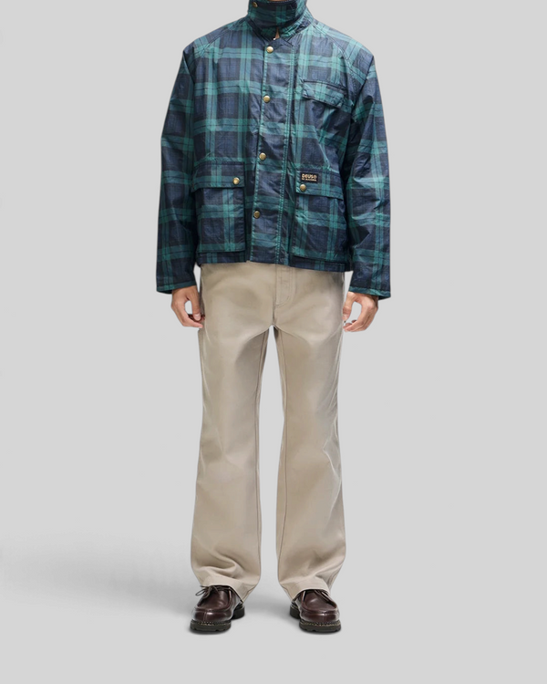 Baffle Haus Marsden hunting jacket in green check with corduroy collar, worn with beige trousers.
