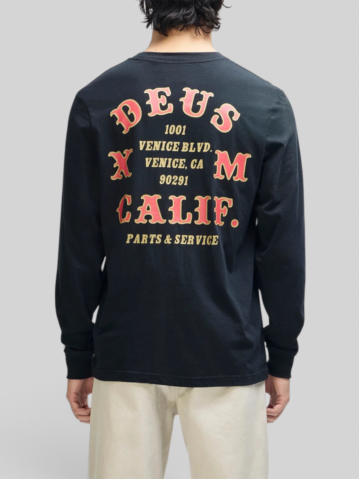 Baffle Haus black long sleeve tee with vintage-style red and yellow graphic print on the back, worn by a man.