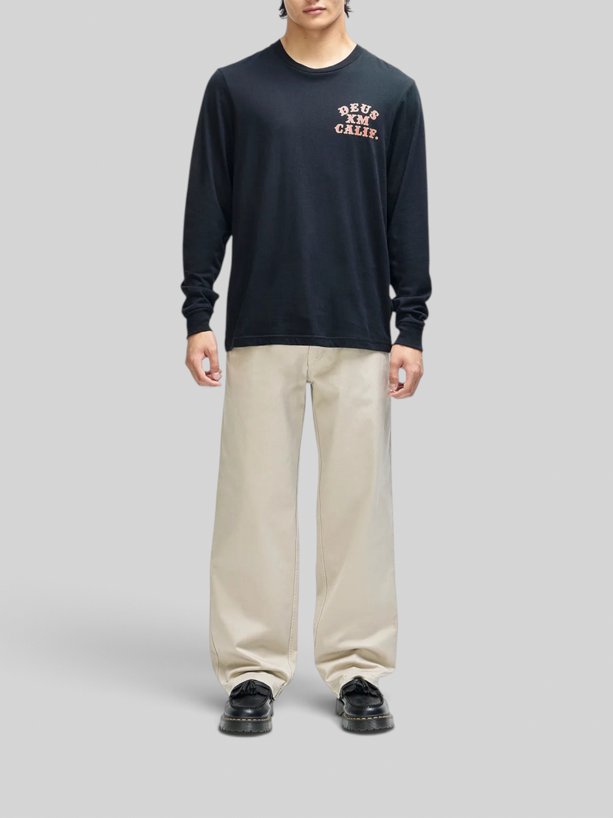 Baffle Haus black long sleeve tee with chest graphic, box fit, worn by a model with beige trousers.