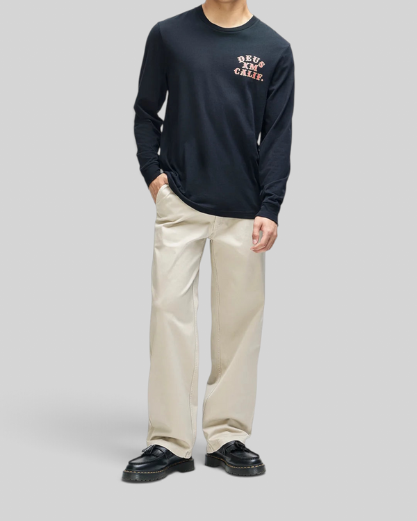 Baffle Haus Quick Strike long sleeve black tee with chest graphic, worn by a model with beige trousers.