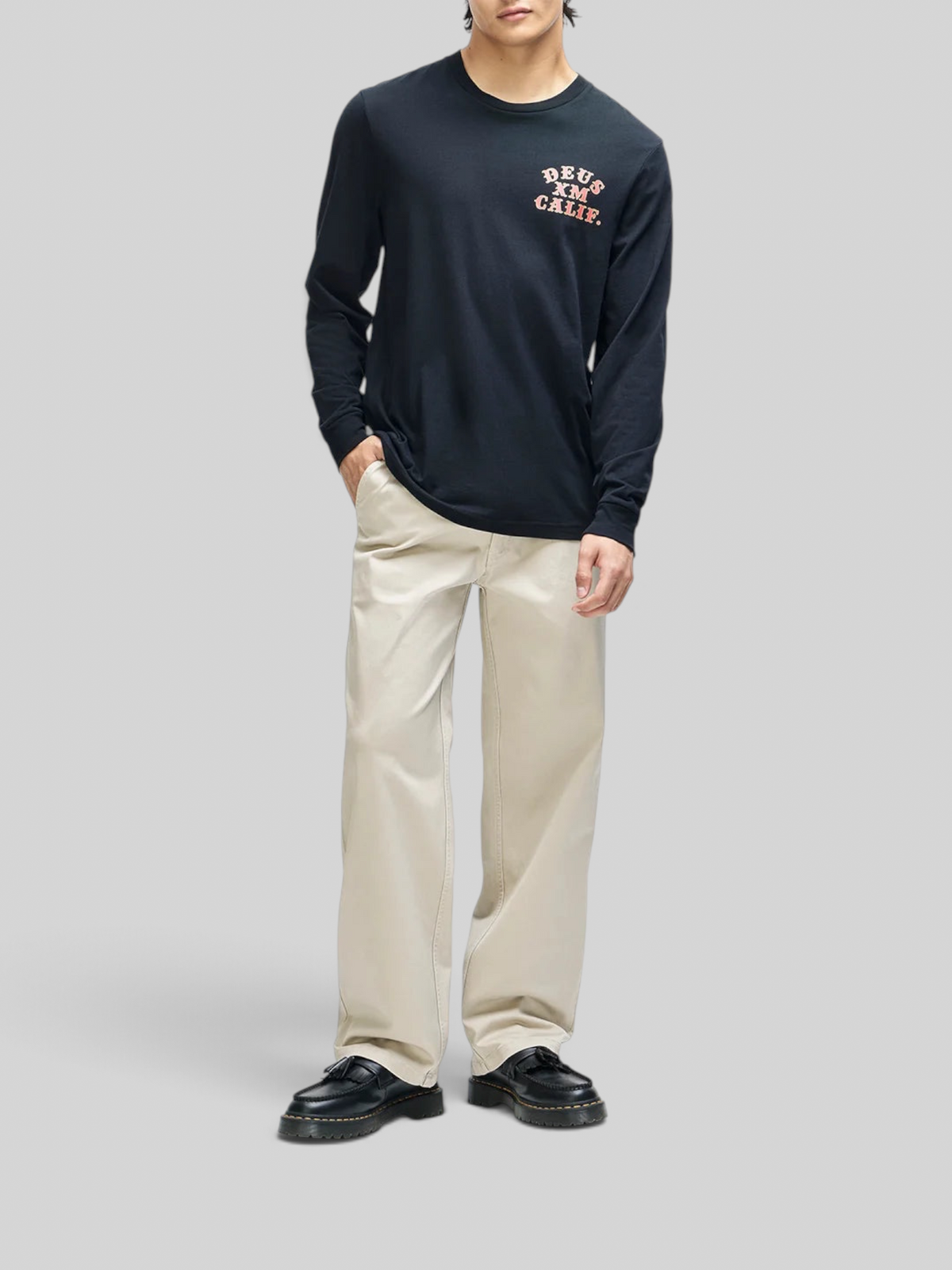 Baffle Haus Quick Strike long sleeve black tee with chest graphic, worn by a model with beige trousers.