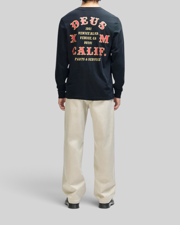 Baffle Haus black long sleeve tee with red and yellow graphic print on the back, worn by a man with light trousers.
