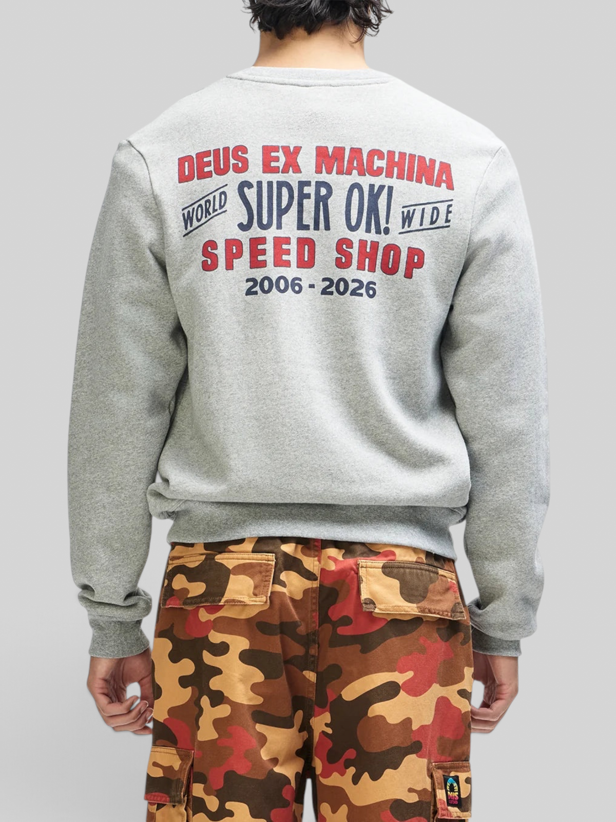 Baffle Haus grey marle crewneck sweatshirt with red and navy graphic print on back, worn with camo cargo pants.