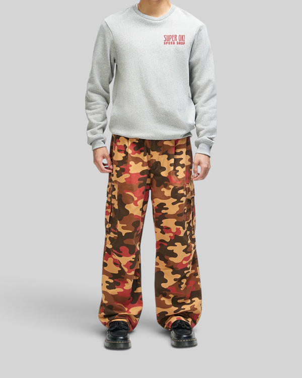 Baffle Haus model wearing a grey marle box fit sweatshirt with red chest graphic and multi-coloured camo cargo pants