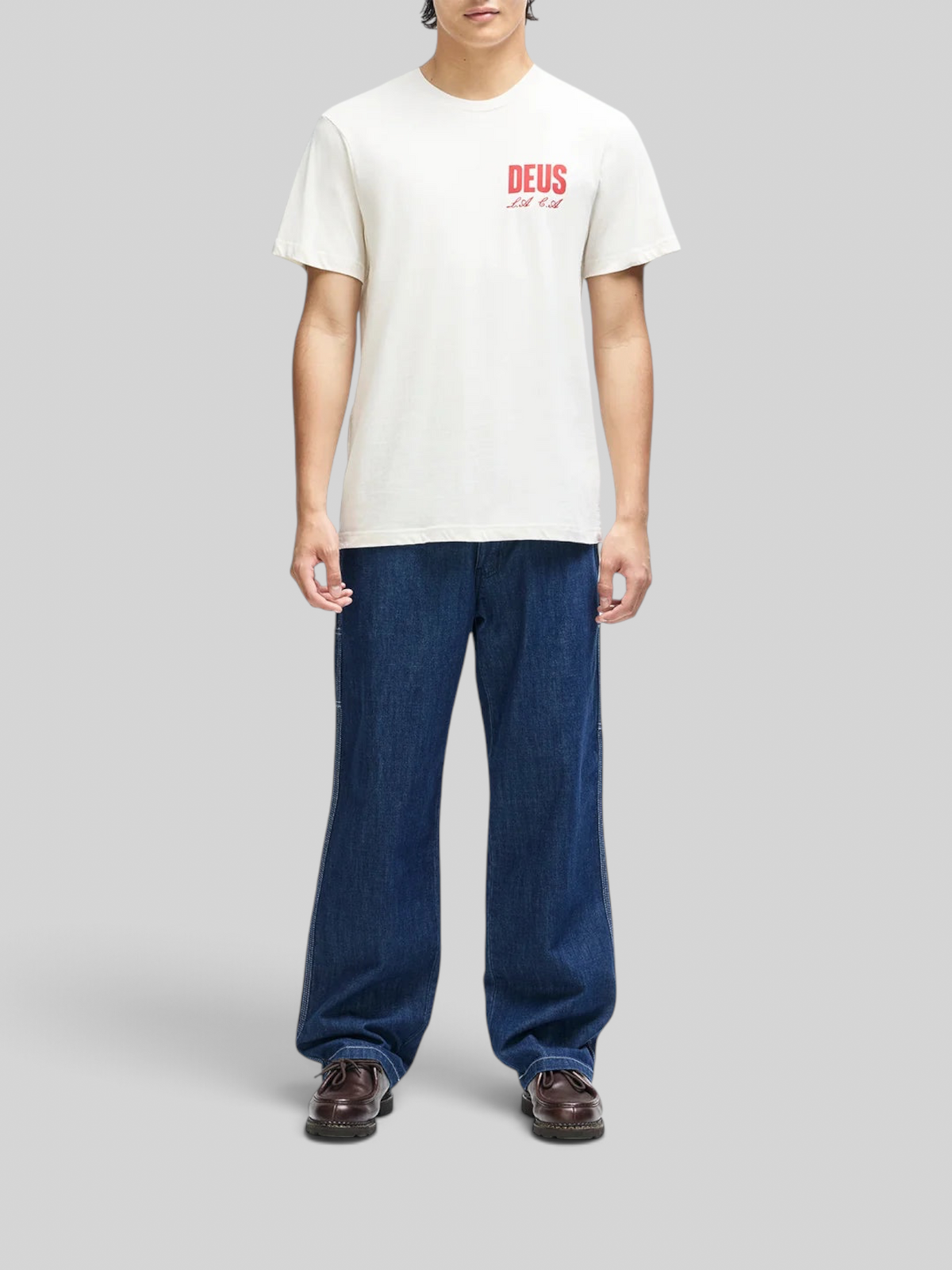 Baffle Haus vintage white box fit organic cotton t-shirt with red chest graphic worn by a model in blue jeans