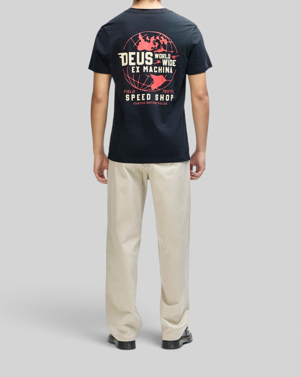 Baffle Haus Global Spark black box fit t-shirt with red and cream globe graphic on back, worn with beige trousers.