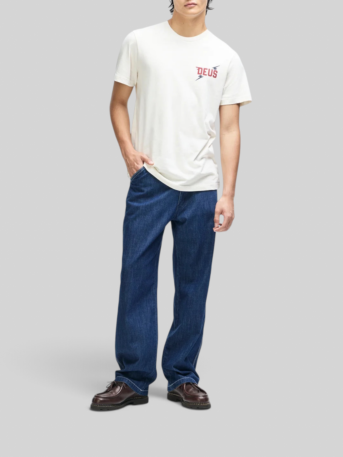 Baffle Haus Global Spark box fit tee in vintage white with chest graphic, worn with blue jeans and brown shoes