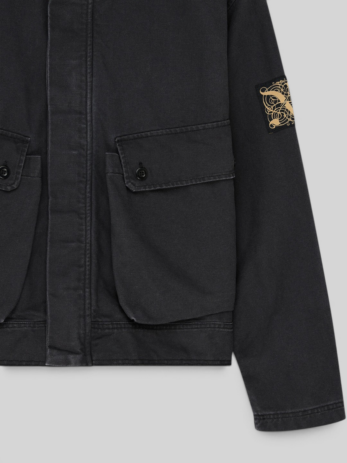 Baffle Haus Common State jacket in overdyed anthracite grey cotton canvas with bellowed pockets and sleeve art label.