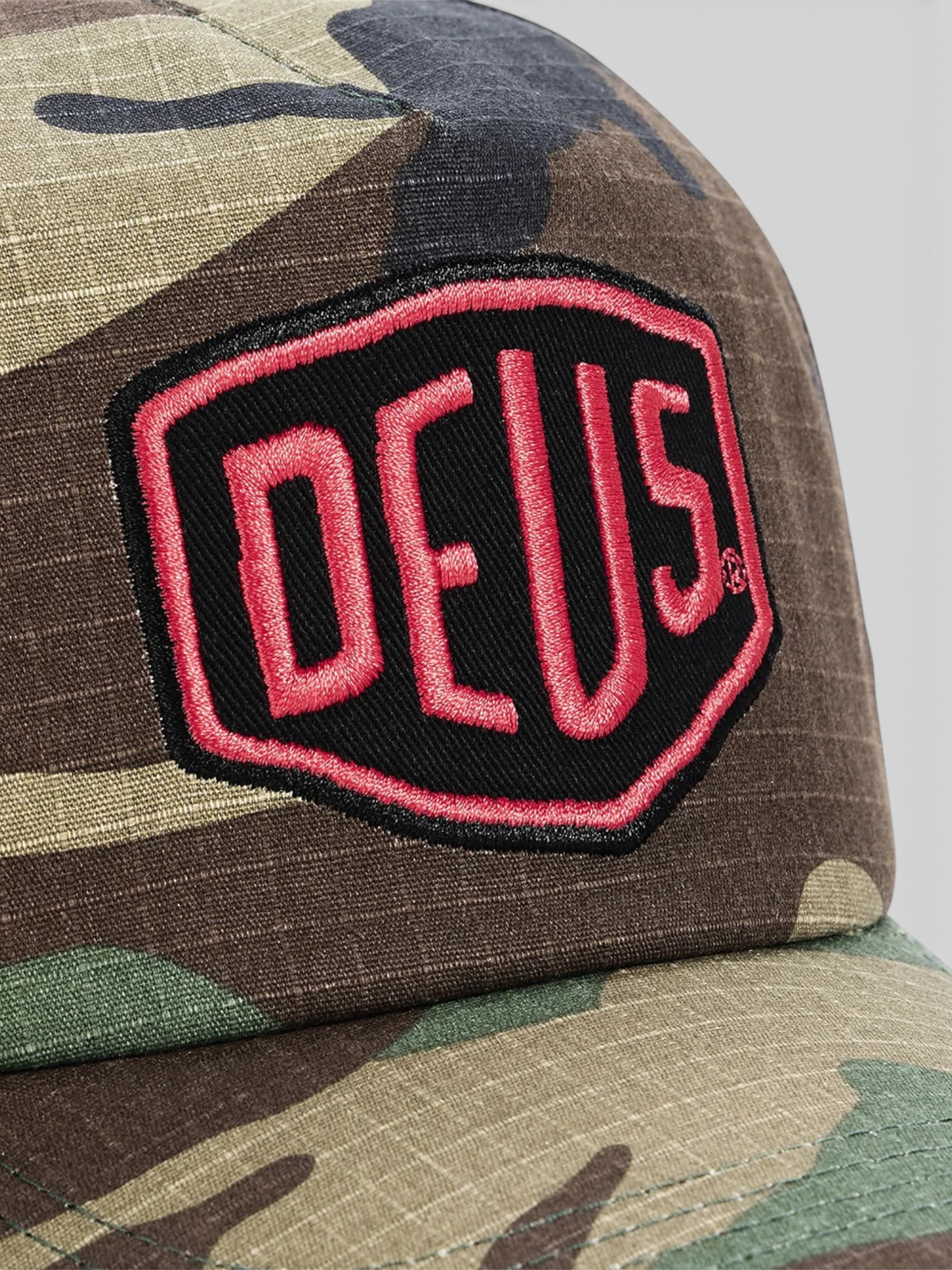 Baffle Haus Paris Shield trucker cap in camo cotton ripstop with a red and black Deus Ex Machina patch