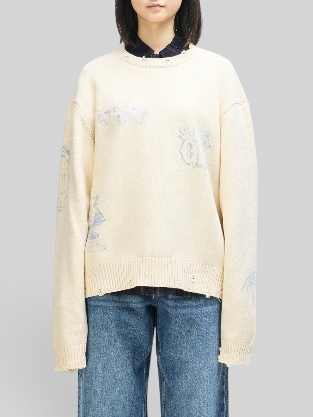 Baffle Haus cream cotton knit crew sweater with blue graphic prints, distressed details, and an oversized fit.