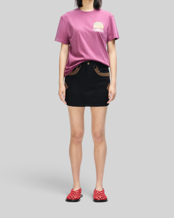 Baffle Haus Daphne Tee in burgundy pigment-dyed cotton with chest pocket logo print worn with a black mini skirt