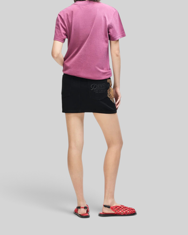 Baffle Haus model wearing a burgundy slim fit tee, black mini skirt with graphic pocket, and red woven sandals