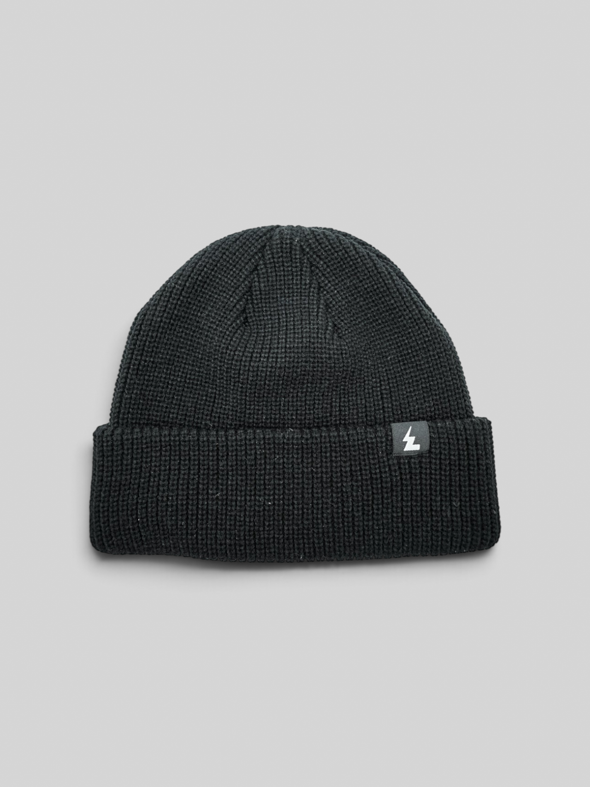 Baffle Haus black acrylic knit beanie with a classic cuffed design and a small woven brand label.