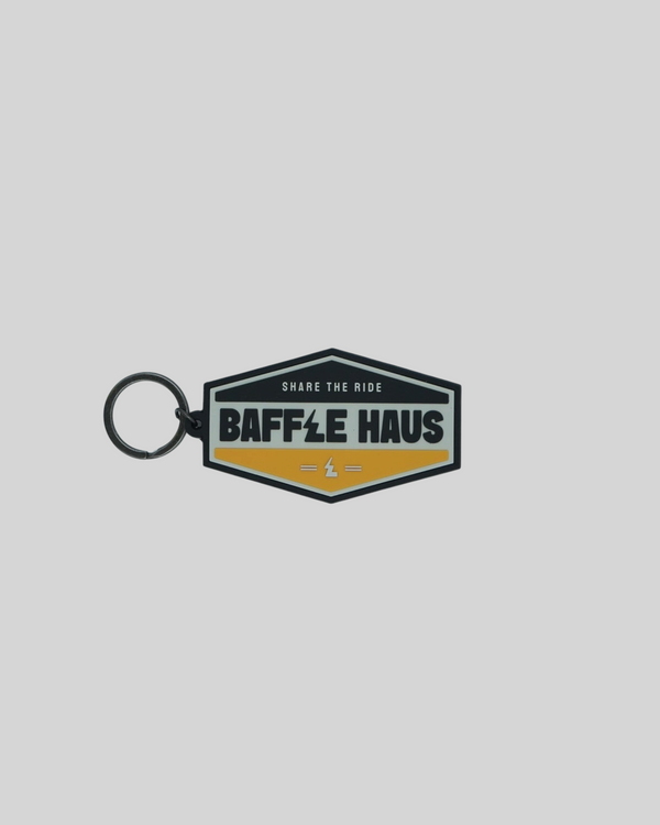 Baffle Haus yellow retro key tag with embossed logo and black split-ring on a light grey background.