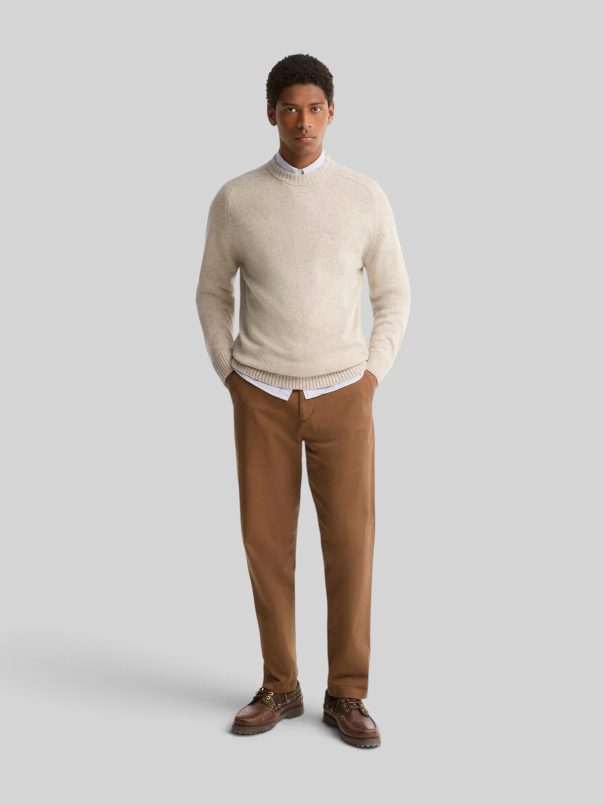 Baffle Haus model wearing a light grey Barbour Newtown lambswool crew neck jumper over a shirt and brown trousers.