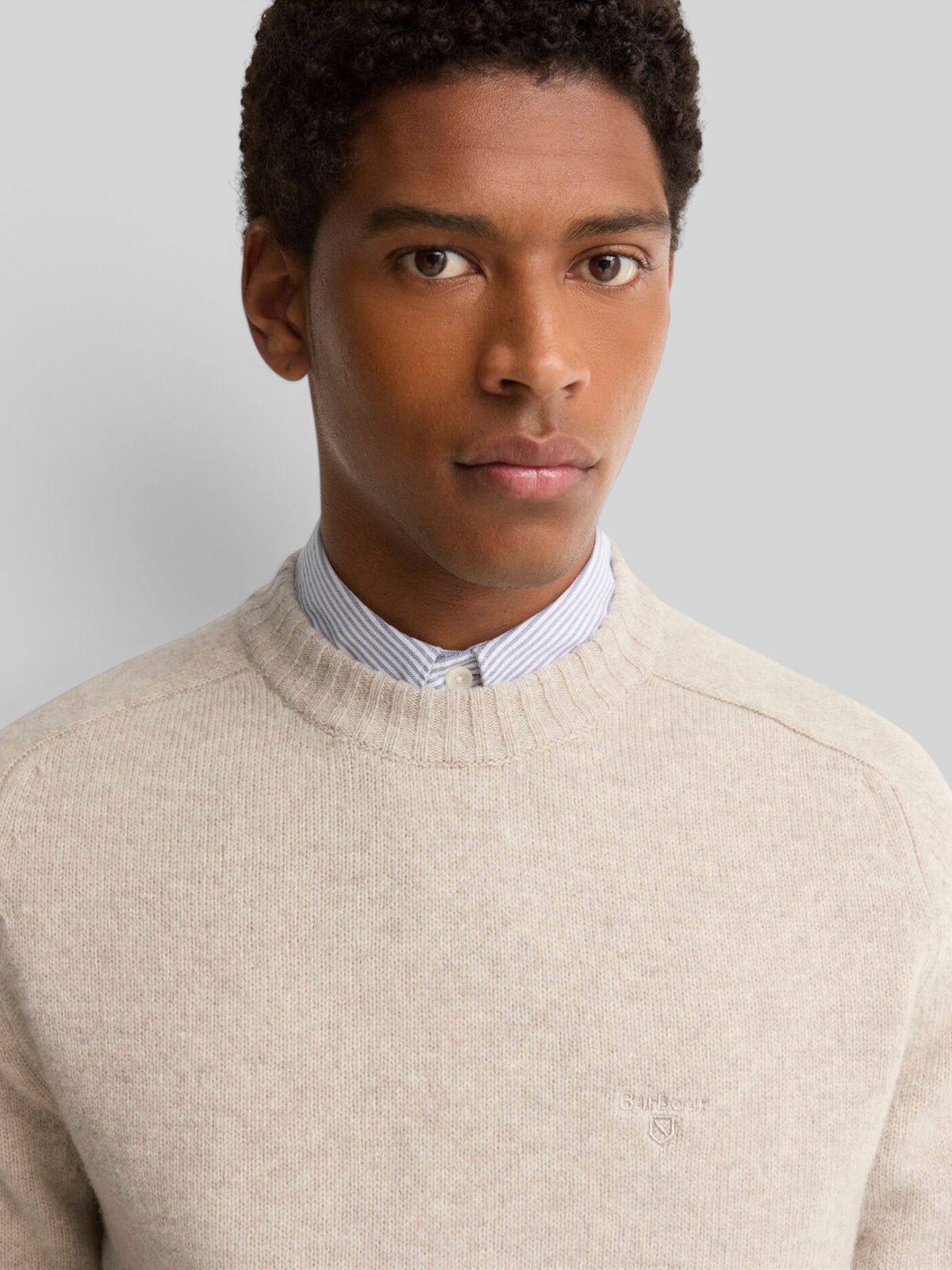 Baffle Haus Barbour light grey lambswool crew neck jumper worn by a man over a striped collared shirt