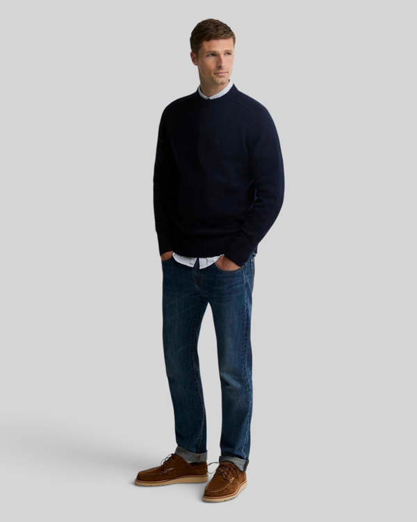Baffle Haus model wearing a navy Barbour Newtown crew neck lambswool jumper with jeans and brown suede shoes.