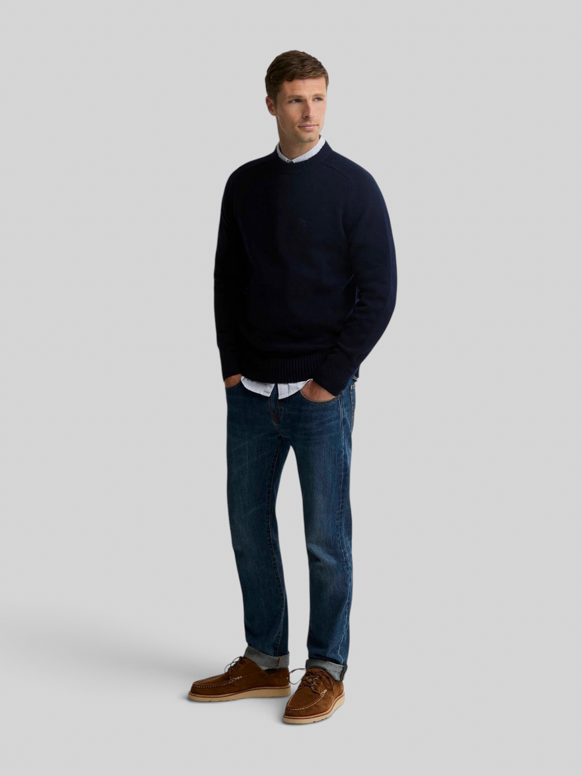 Baffle Haus model wearing a navy Barbour Newtown crew neck lambswool jumper with jeans and brown suede shoes.