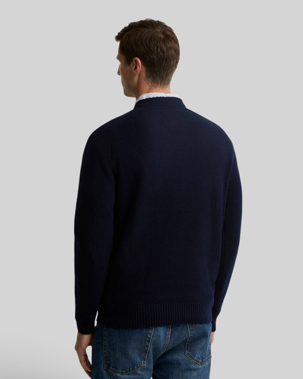 A man wearing a navy Baffle Haus Newtown crew neck jumper in lambswool, shown from the back view.