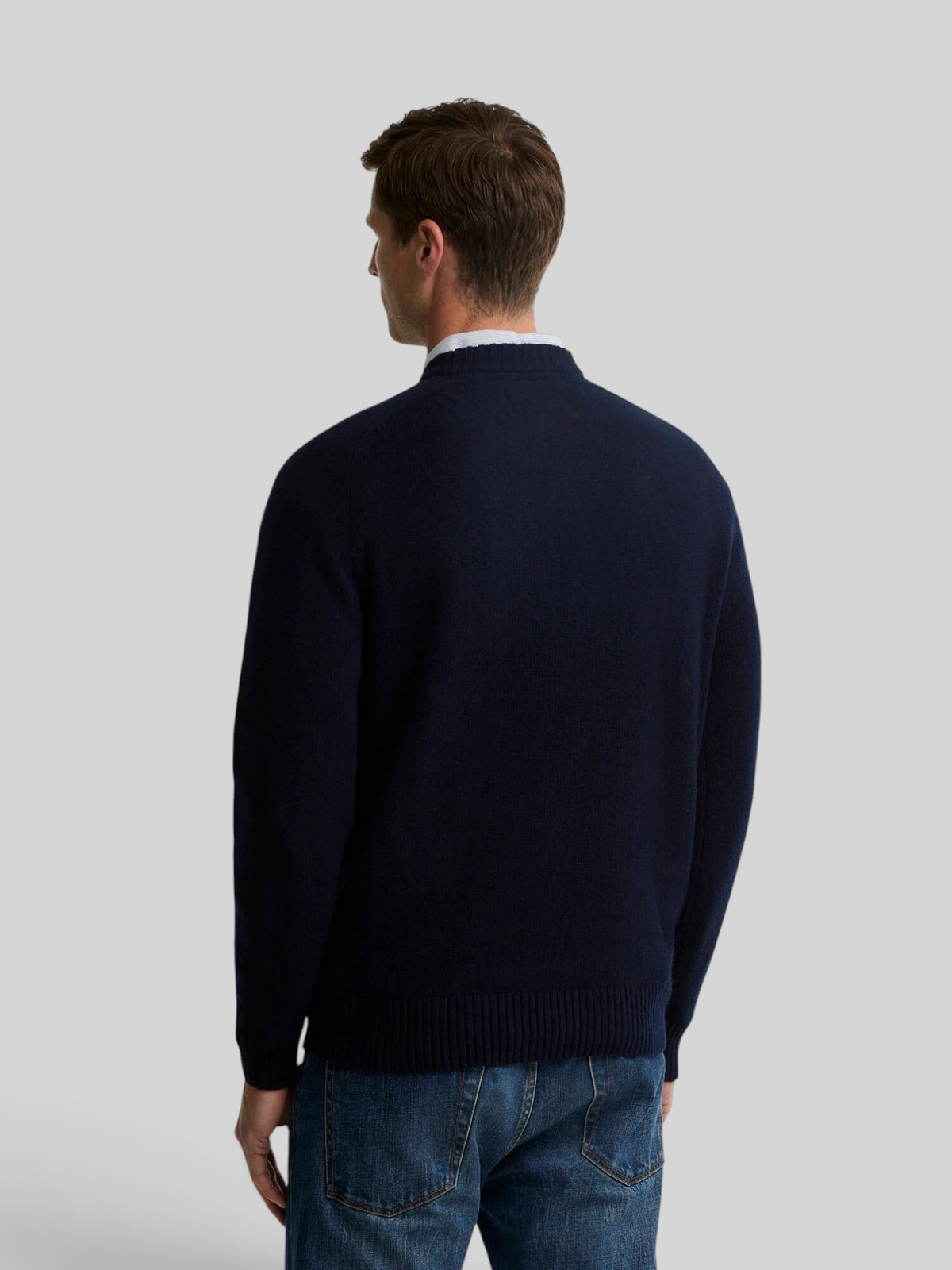 A man wearing a navy Baffle Haus Newtown crew neck jumper in lambswool, shown from the back view.