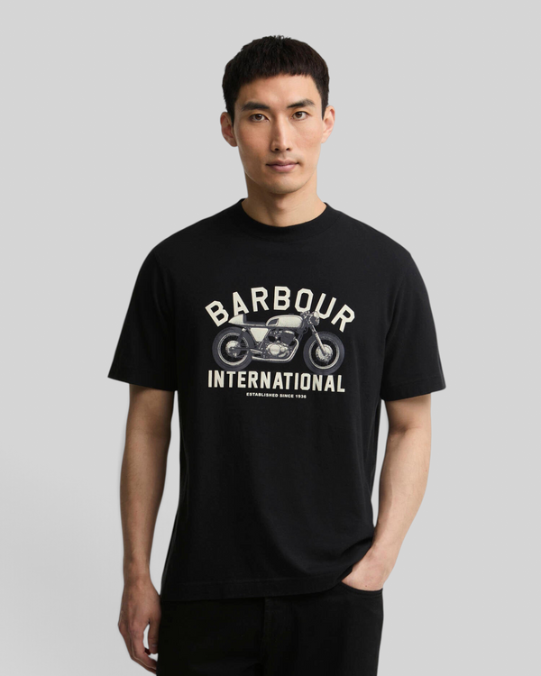 A man wearing a black Baffle Haus Eric graphic cotton t-shirt featuring a vintage motorcycle print on the chest.