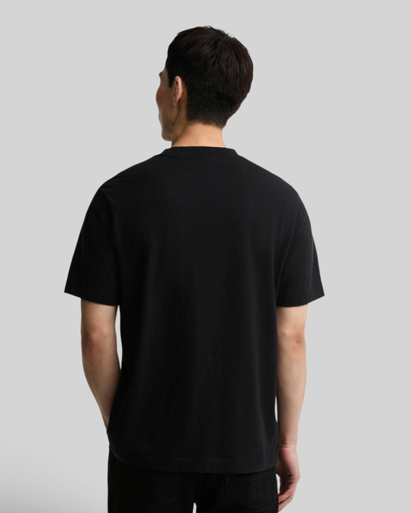 Back view of a man wearing a Baffle Haus black 100% cotton relaxed-fit t-shirt with open cuffs.