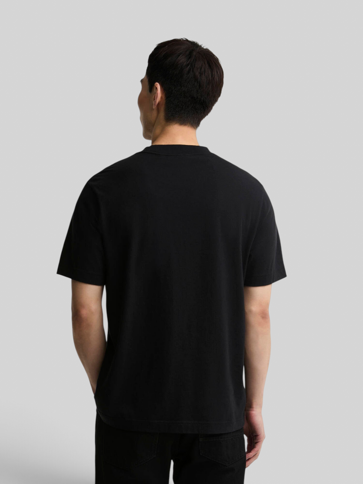 Back view of a man wearing a Baffle Haus black 100% cotton relaxed-fit t-shirt with open cuffs.