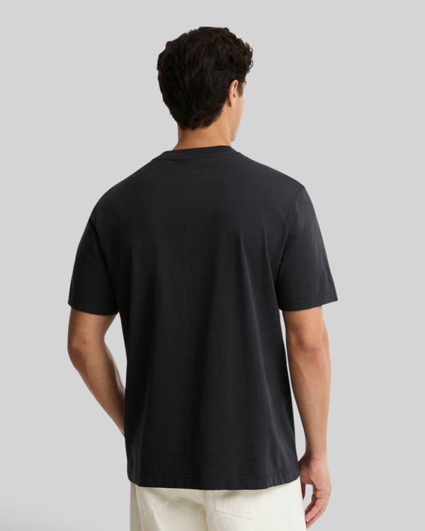 Back view of a man wearing a plain black Baffle Haus cotton crew neck t-shirt with short sleeves