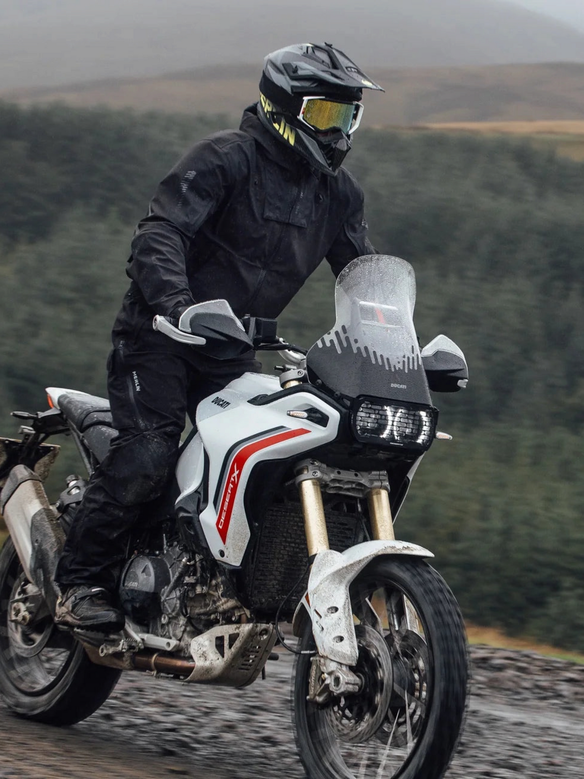 Baffle Haus Merlin Raptor D3O black laminated adventure motorcycle jacket worn by a rider on a Ducati DesertX