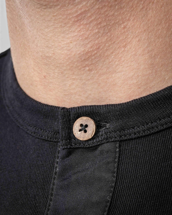 Baffle Haus 1927 Henley long sleeve shirt in deep black cotton with a detailed view of the natural coconut button.