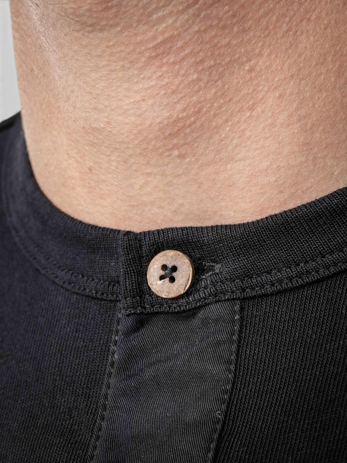 Baffle Haus 1927 Henley long sleeve shirt in deep black cotton with a detailed view of the natural coconut button.
