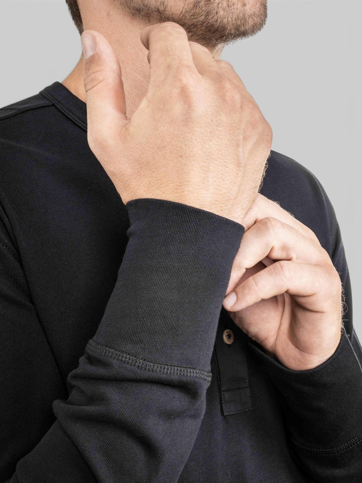 Baffle Haus 1927 Henley long sleeve shirt in deep black cotton with coconut button detail on a man