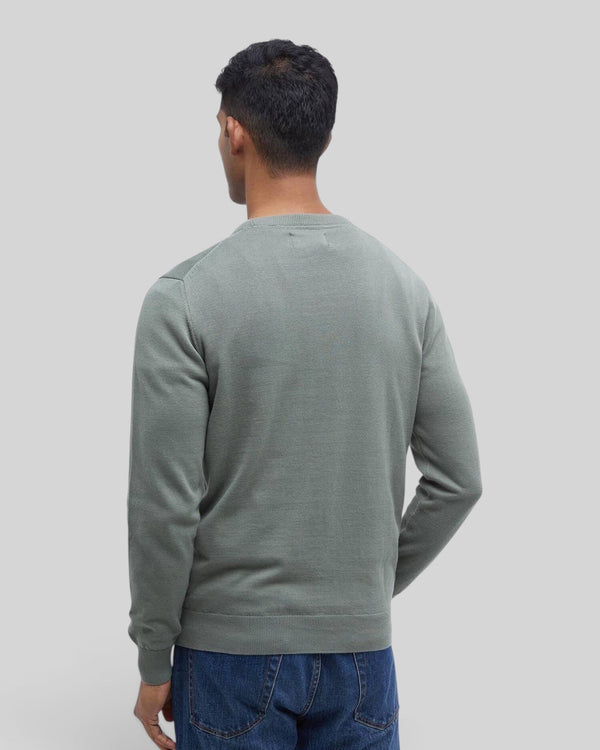 Back view of a man wearing a Baffle Haus agave green Pima cotton crew neck sweater with blue jeans