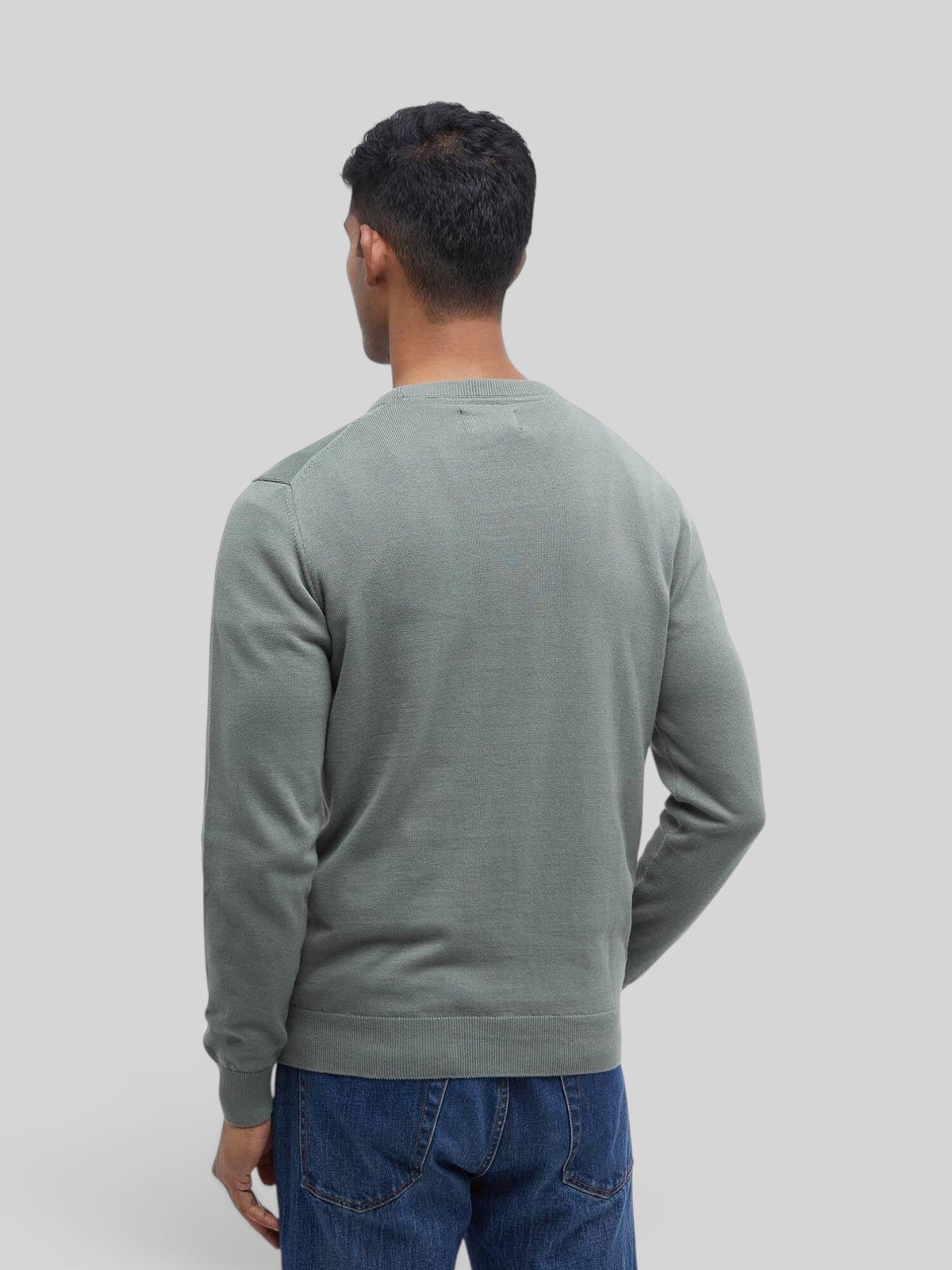 Back view of a man wearing a Baffle Haus agave green Pima cotton crew neck sweater with blue jeans