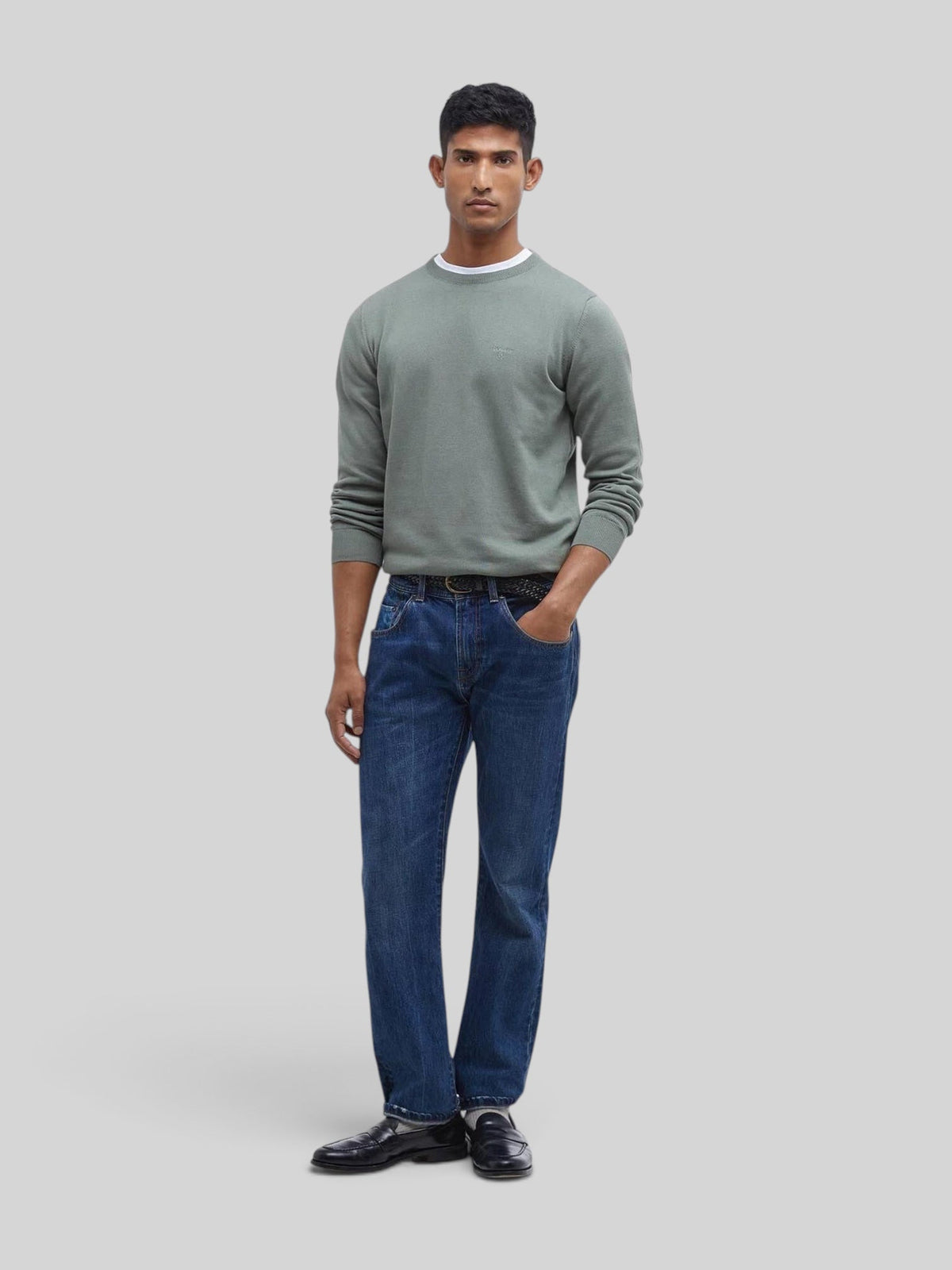 Baffle Haus model wearing an agave green Pima cotton crew neck sweater with embroidered logo over blue jeans