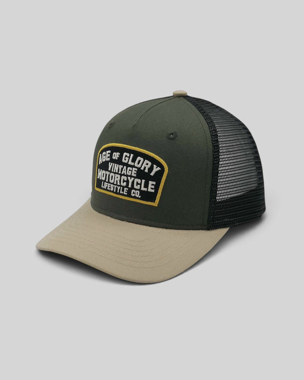 Baffle Haus Buddy trucker cap in army green with a beige brim, black mesh back, and vintage motorcycle patch.