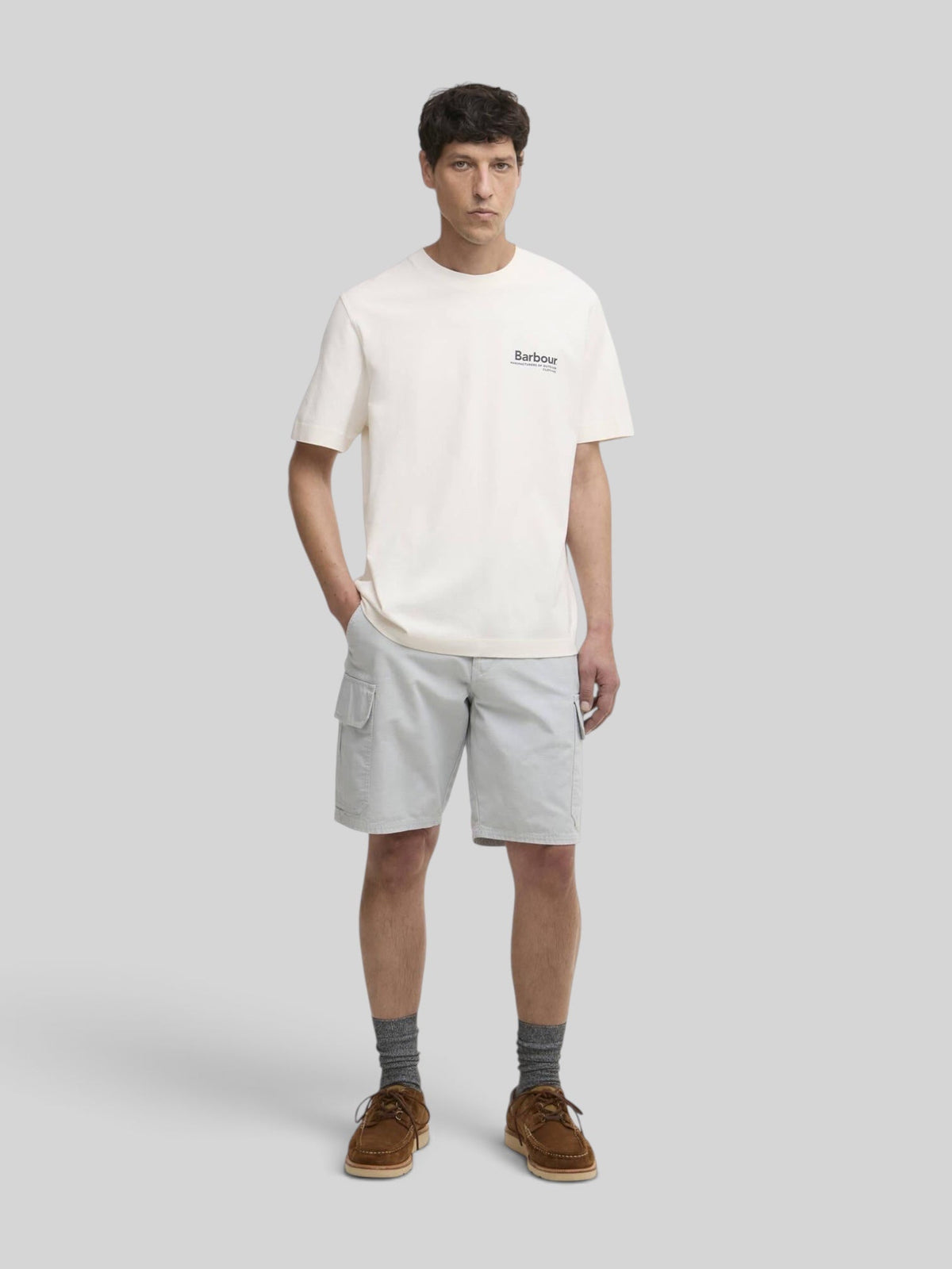 Baffle Haus model wearing a neutral Barbour Wildfell relaxed fit cotton graphic t-shirt with grey cargo shorts