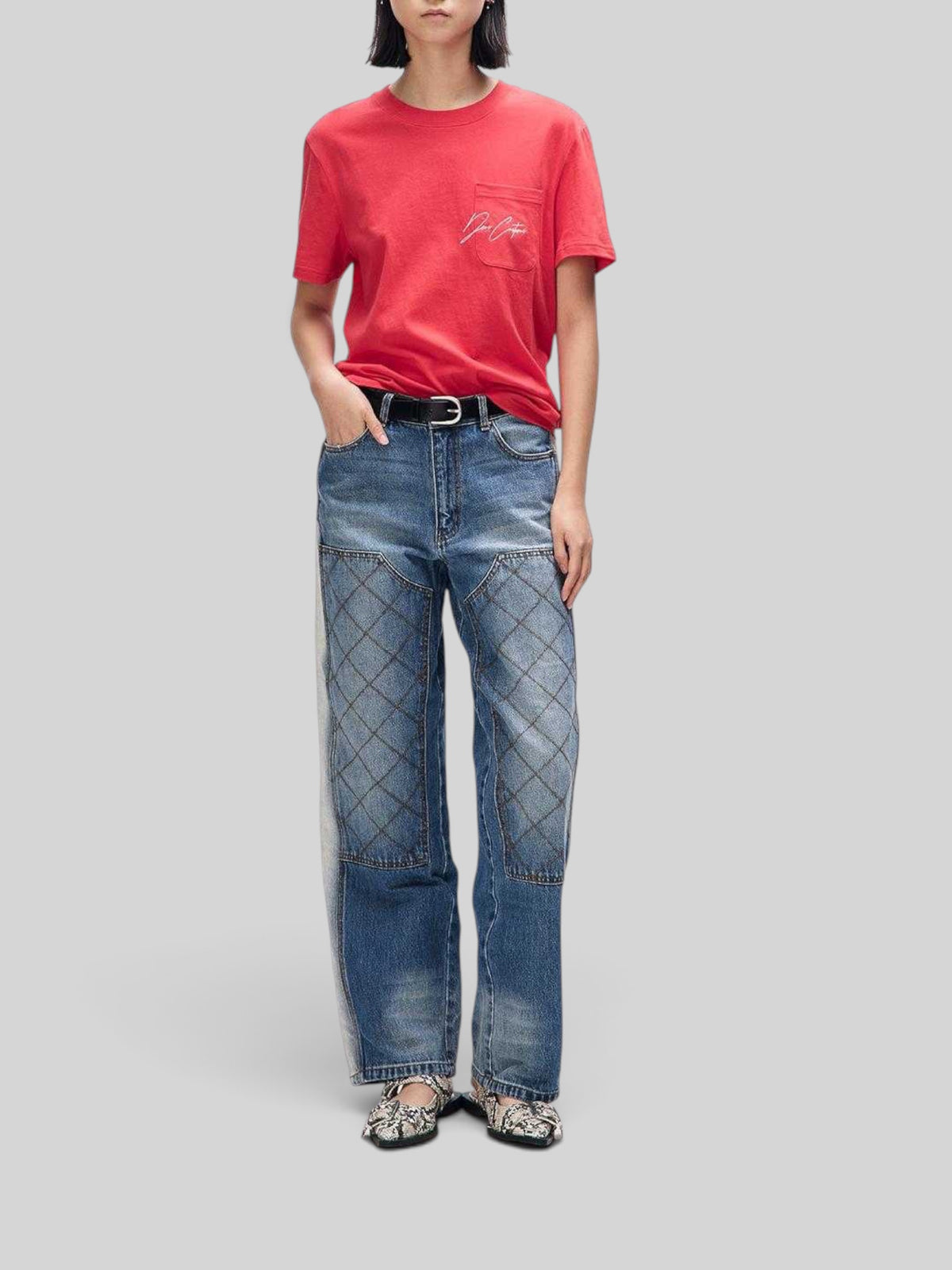 Baffle Haus Bird Scratch Tee in poinsettia red with chest pocket and white embroidery, worn with quilted denim jeans.