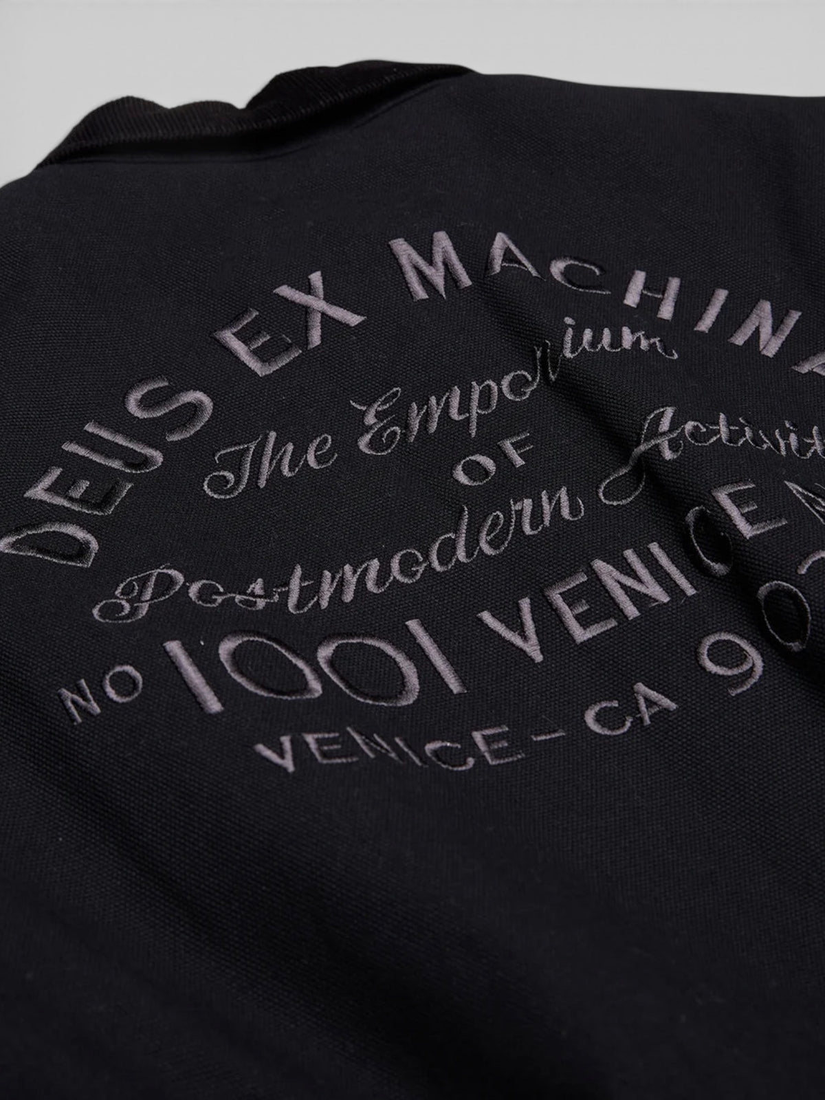 Baffle Haus black cotton canvas workwear jacket featuring detailed embroidered Deus Ex Machina address branding