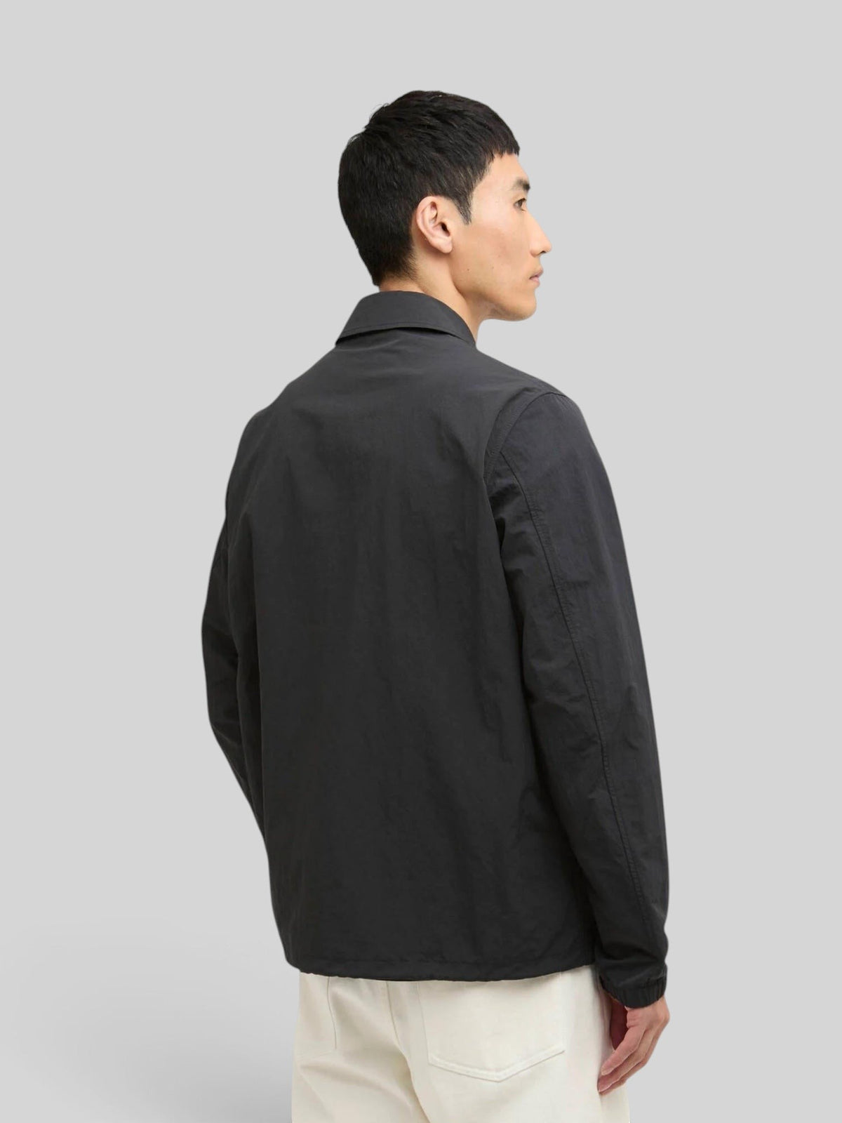 Baffle Haus International Coach Casual Jacket in black with a classic collar and drawcord hem, worn by a model.