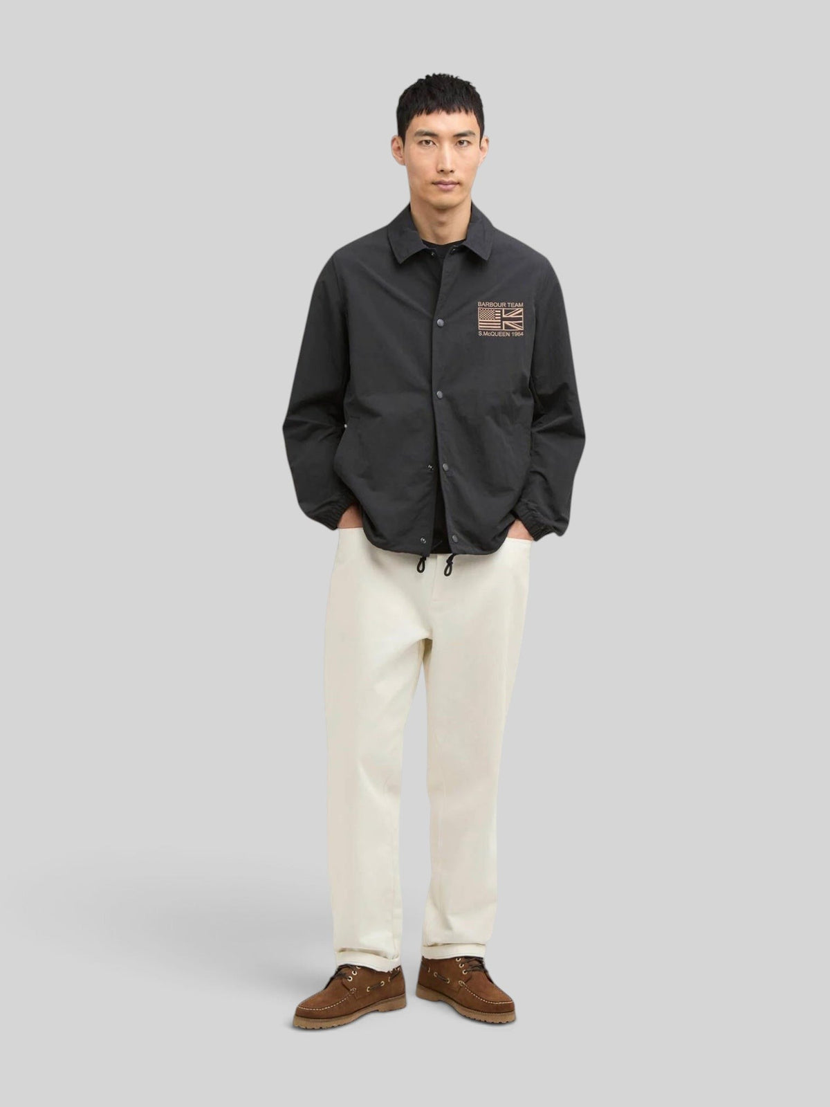 Baffle Haus black coach jacket with stud front, sit-down collar, and Steve McQueen embroidery on the chest.
