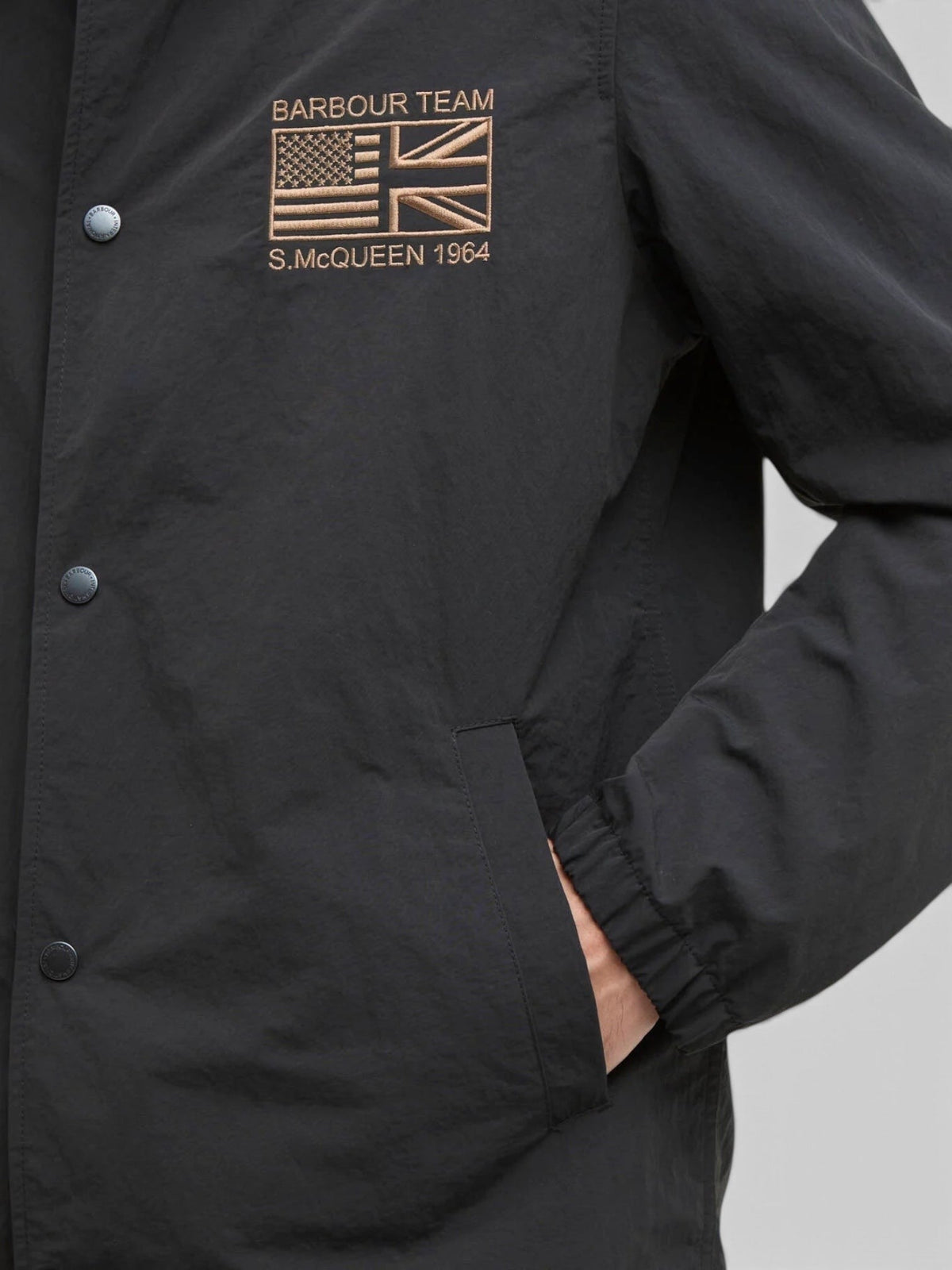 Baffle Haus black casual coach jacket with stud front fastening and Steve McQueen embroidery on the chest